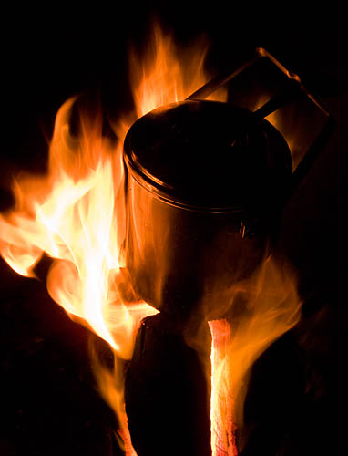 A billy can on top of the fire log. -   Gary Waidson - Ravenlore Bushcraft and Wilderness skills.